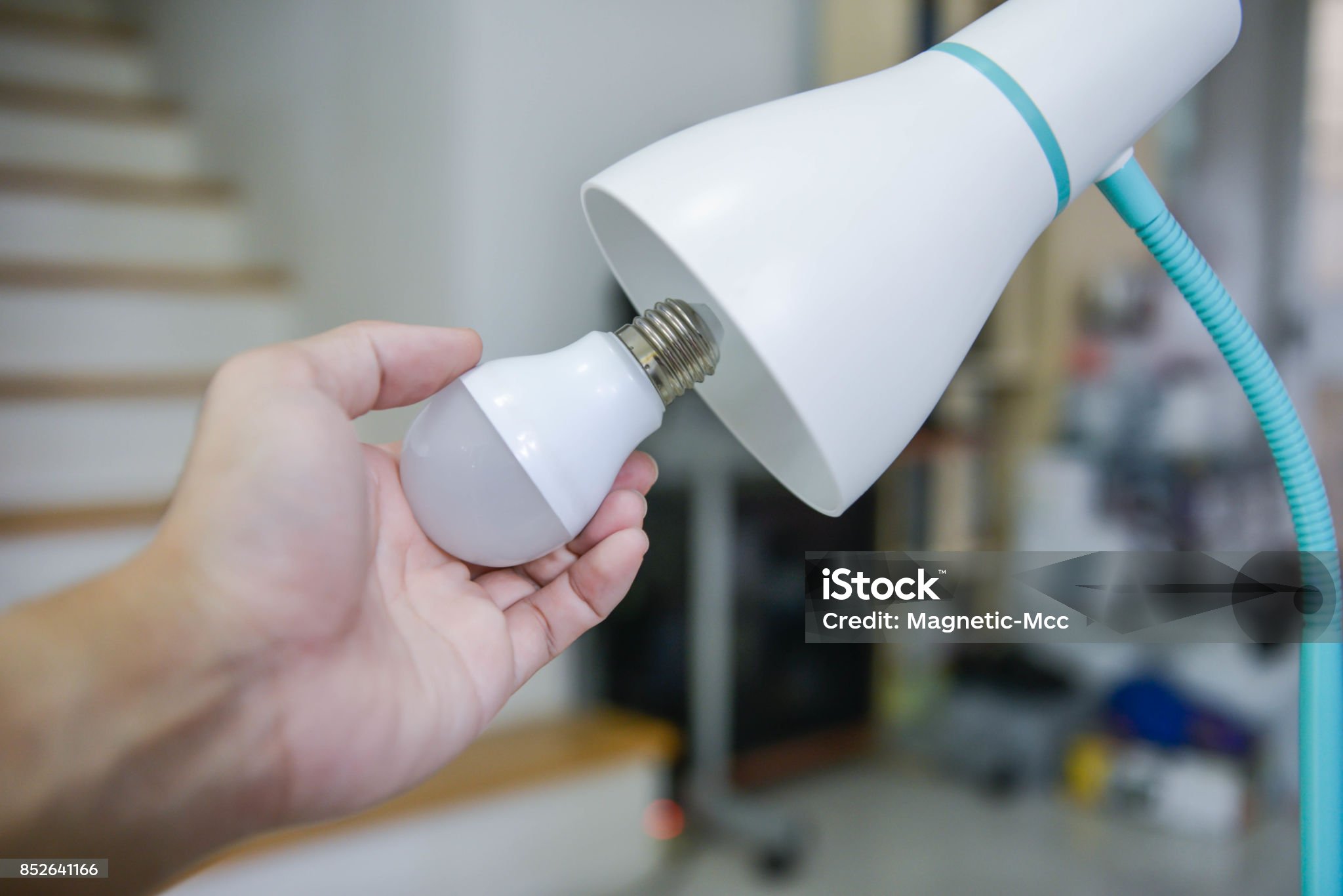 Mano instalando bombilla inteligente para instalar domótica paso a paso en una lámpara de escritorio